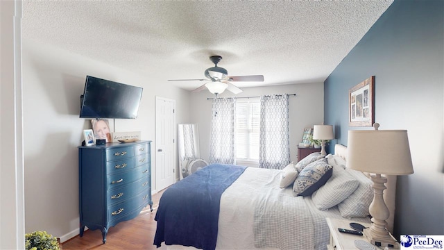 bedroom with hardwood / wood-style flooring, a textured ceiling, and ceiling fan