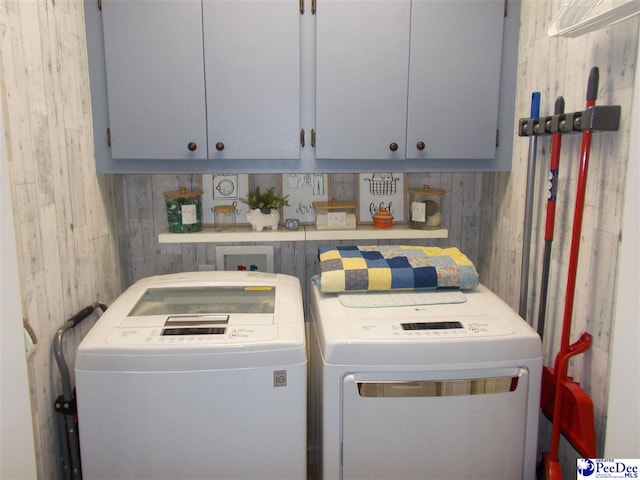 clothes washing area with cabinets and washing machine and dryer