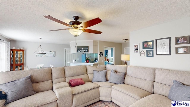 living room with ceiling fan and a textured ceiling