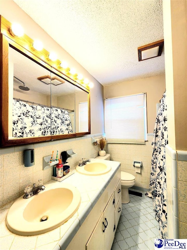 bathroom with vanity, tile walls, a textured ceiling, and toilet