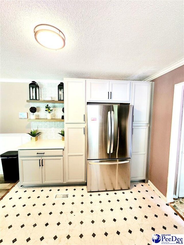 kitchen with crown molding, stainless steel fridge, and a textured ceiling