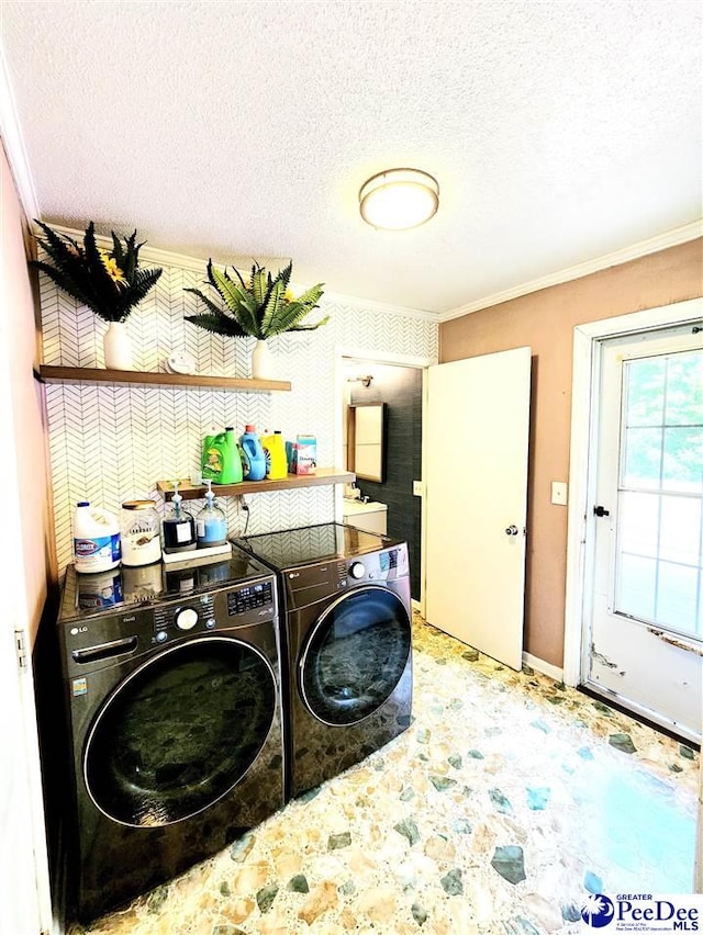 clothes washing area with ornamental molding, washing machine and clothes dryer, and a textured ceiling