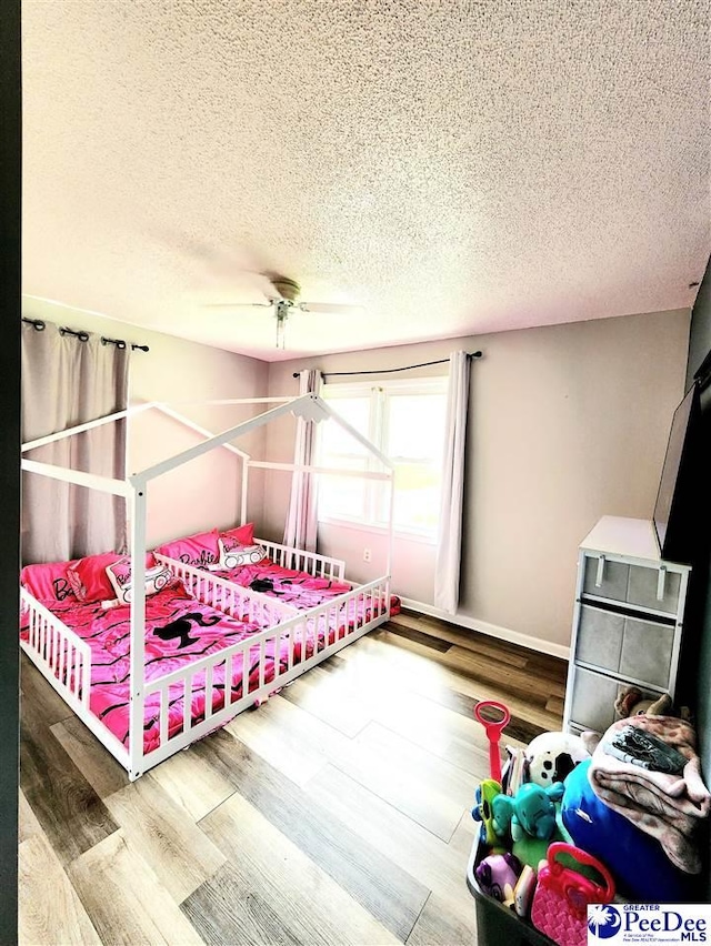 bedroom with hardwood / wood-style flooring, ceiling fan, and a textured ceiling