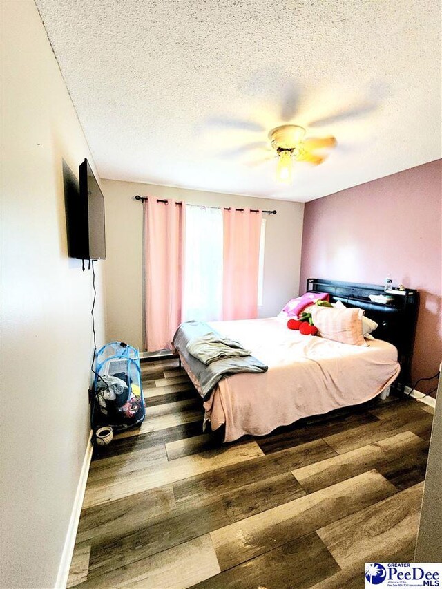 bedroom with ceiling fan, wood-type flooring, and a textured ceiling