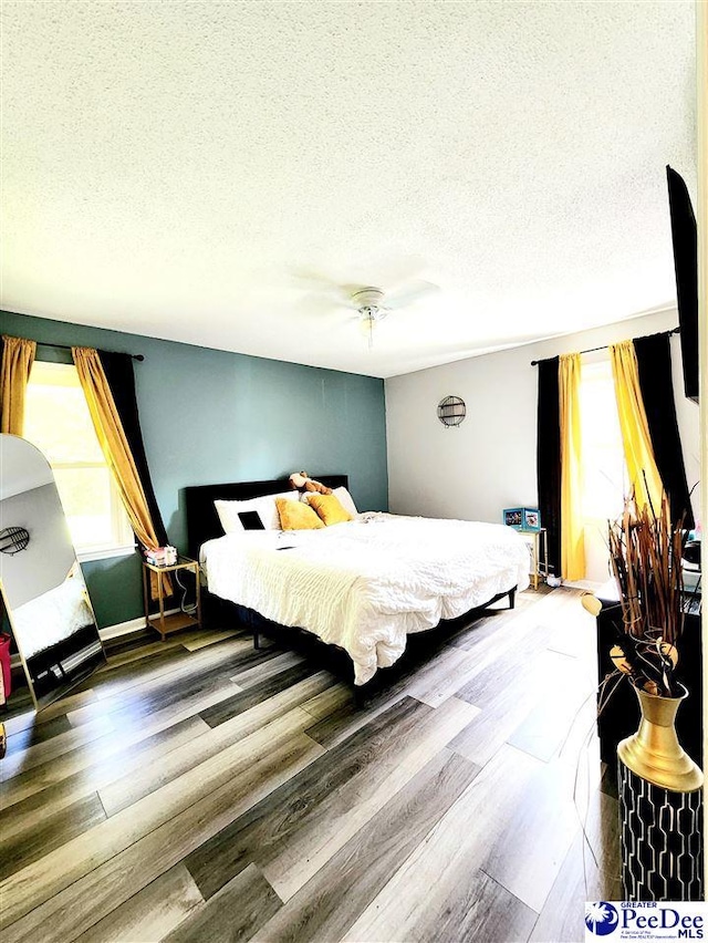 bedroom featuring ceiling fan, wood-type flooring, and a textured ceiling