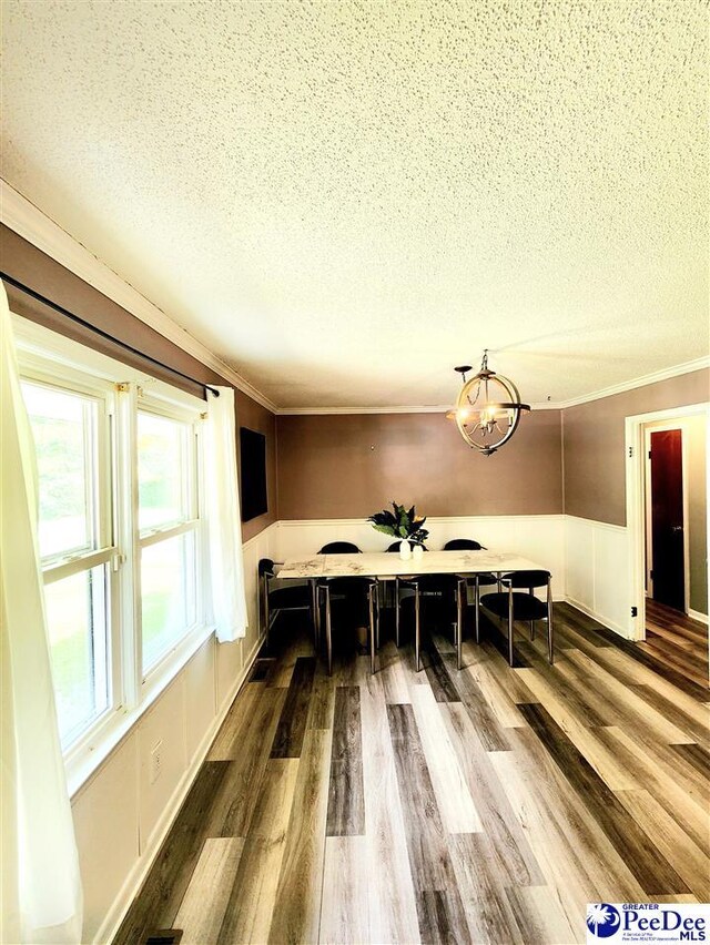 dining area with ornamental molding, wood-type flooring, an inviting chandelier, and a textured ceiling