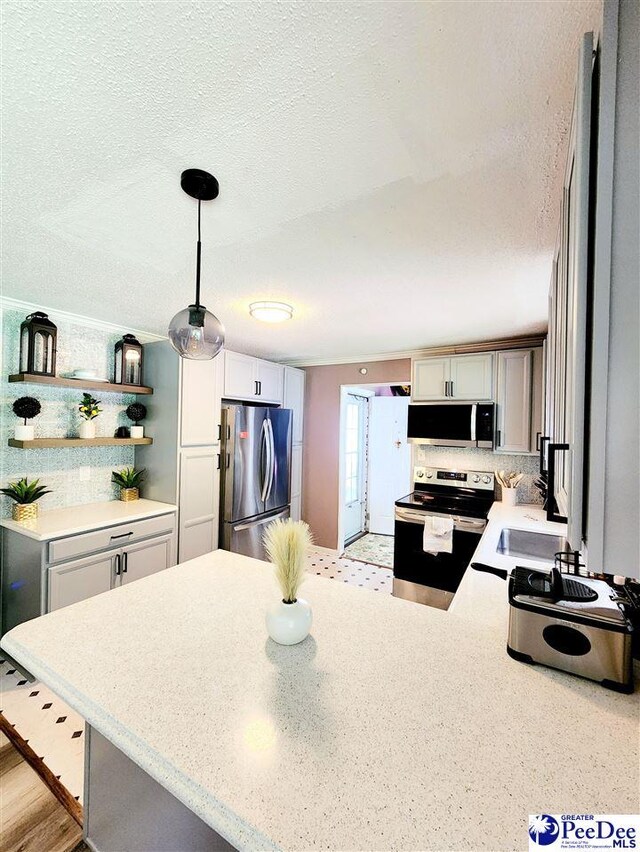 kitchen featuring pendant lighting, appliances with stainless steel finishes, tasteful backsplash, a textured ceiling, and kitchen peninsula