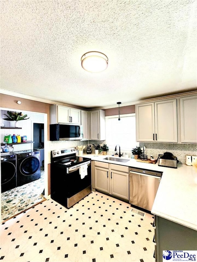 kitchen with gray cabinets, separate washer and dryer, sink, hanging light fixtures, and stainless steel appliances