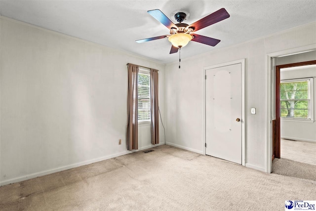 unfurnished bedroom featuring ceiling fan, ornamental molding, light carpet, and a textured ceiling