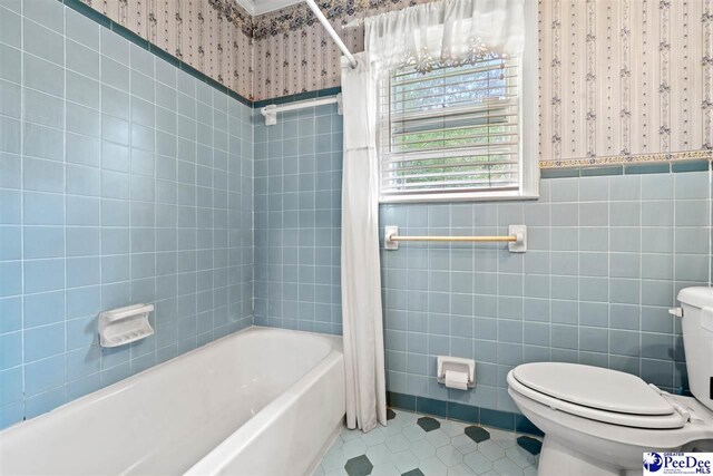 bathroom featuring shower / bath combination with curtain, tile patterned floors, toilet, and tile walls