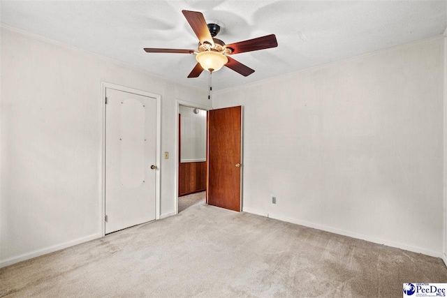 spare room featuring crown molding, ceiling fan, and light carpet