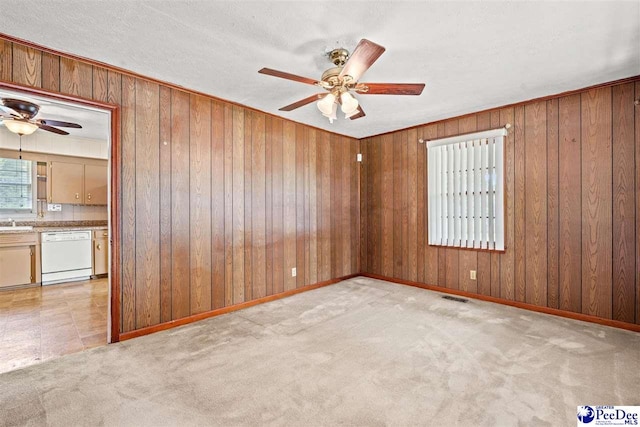 spare room with light carpet, wooden walls, and ceiling fan