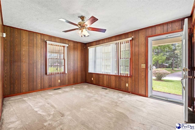 spare room featuring ceiling fan, light carpet, and a textured ceiling