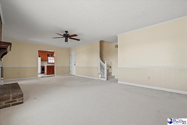 unfurnished living room with a wainscoted wall, stairs, crown molding, a textured ceiling, and carpet floors