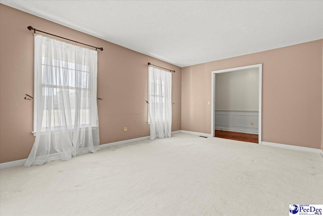 carpeted empty room with a textured ceiling and baseboards