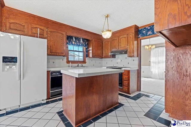 kitchen featuring light tile patterned floors, under cabinet range hood, white refrigerator with ice dispenser, range with electric stovetop, and tile counters