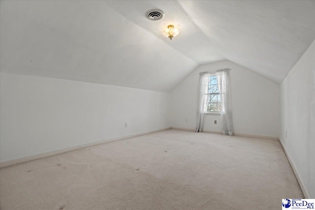 additional living space with lofted ceiling, carpet flooring, visible vents, and baseboards