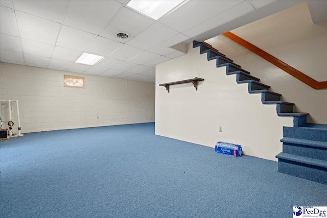 finished below grade area featuring concrete block wall, carpet, visible vents, a drop ceiling, and stairs