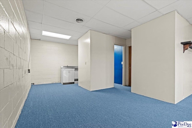 basement with concrete block wall, visible vents, carpet flooring, a paneled ceiling, and a sink