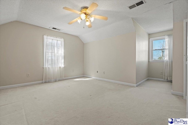 additional living space with lofted ceiling, baseboards, visible vents, and a textured ceiling