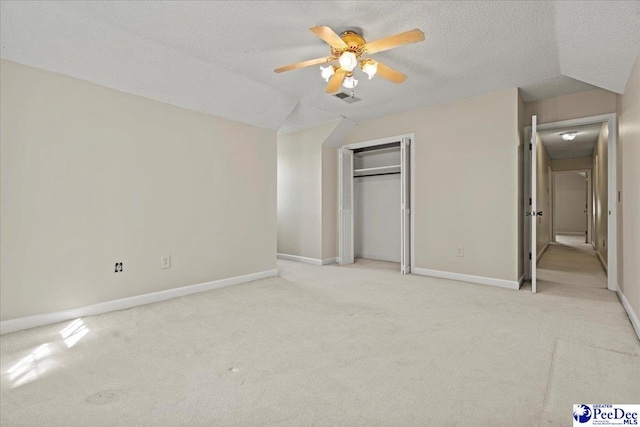 unfurnished bedroom with a textured ceiling, light carpet, visible vents, baseboards, and a closet