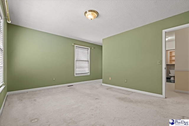 unfurnished bedroom featuring carpet, visible vents, baseboards, and a textured ceiling