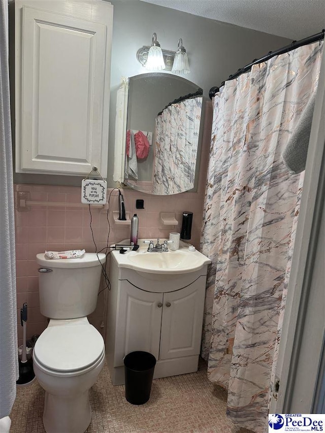 bathroom featuring vanity, a textured ceiling, tile walls, and toilet