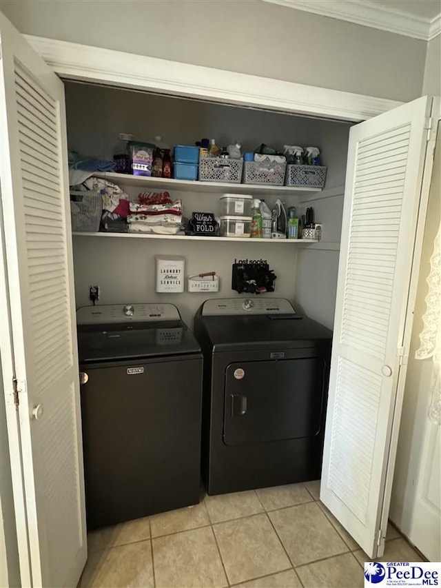 clothes washing area featuring crown molding, washing machine and clothes dryer, and light tile patterned flooring