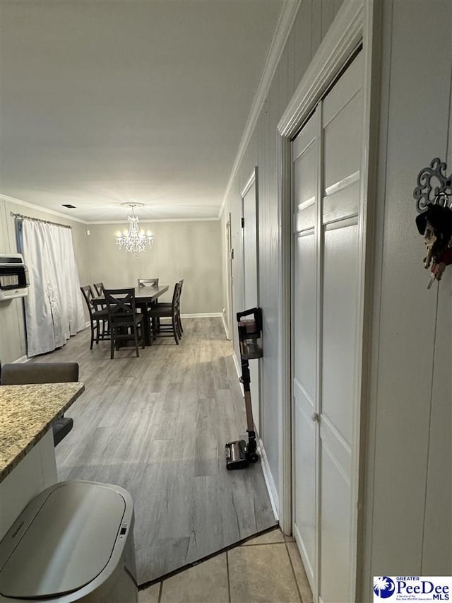 dining area featuring crown molding, a notable chandelier, and light wood-type flooring