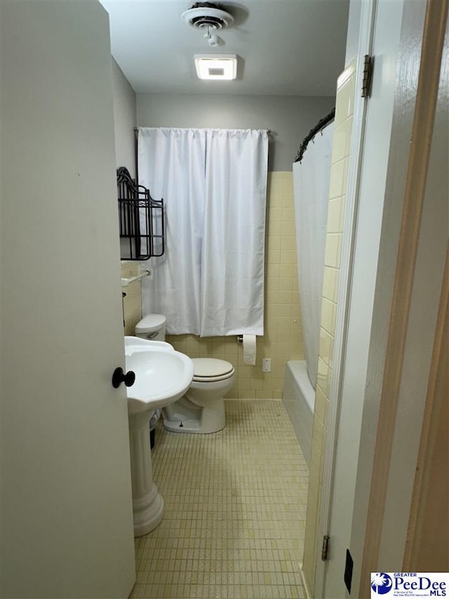 bathroom with shower / bath combo, tile patterned floors, and toilet