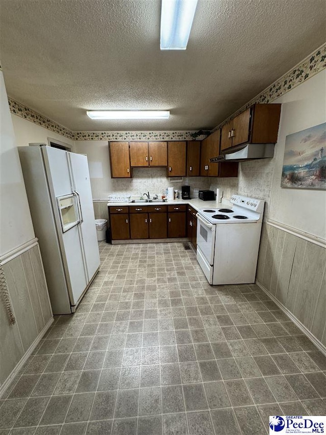 1816 Southern Acres Loop, Dillon, SC 29536 - kitchen with white appliances, under cabinet range hood, a textured ceiling, light countertops, and wainscoting