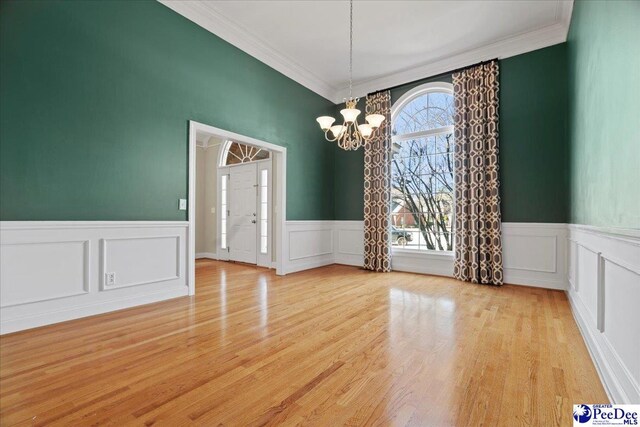 spare room with a notable chandelier, light hardwood / wood-style flooring, and ornamental molding