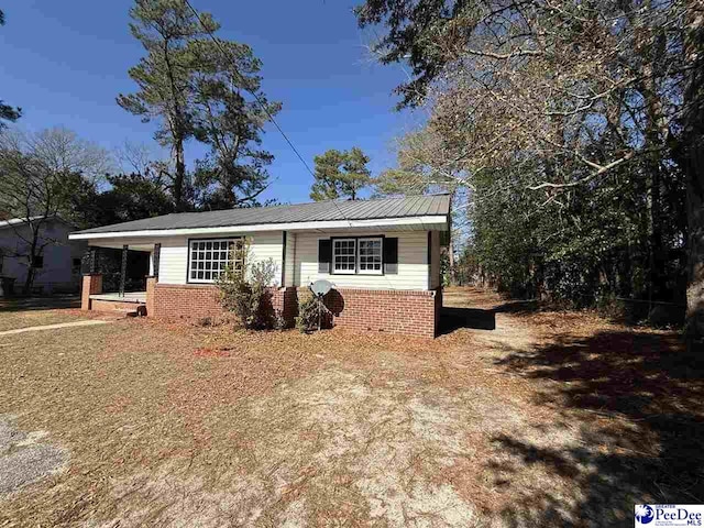 view of front facade featuring brick siding and metal roof