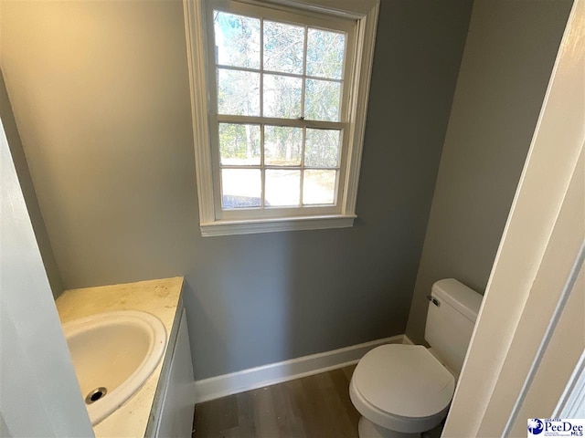 bathroom with vanity, toilet, wood finished floors, and baseboards