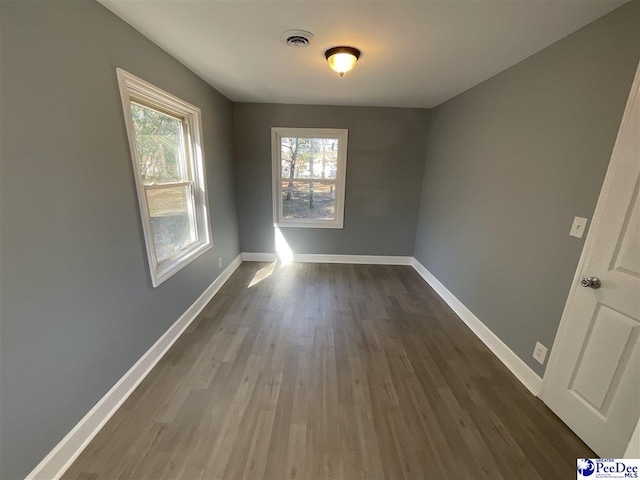 empty room with visible vents, baseboards, and dark wood-style flooring