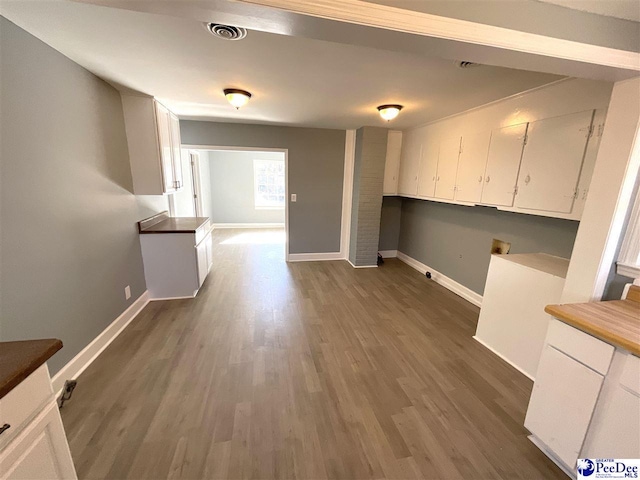 unfurnished dining area with dark wood-type flooring, baseboards, and visible vents