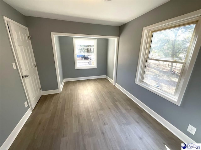 unfurnished bedroom featuring wood finished floors, baseboards, and a closet