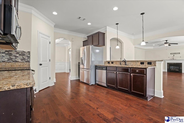 1635 Lake Wateree Dr, Florence, SC 29501 - kitchen with arched walkways, dark brown cabinets, a ceiling fan, crown molding, and appliances with stainless steel finishes