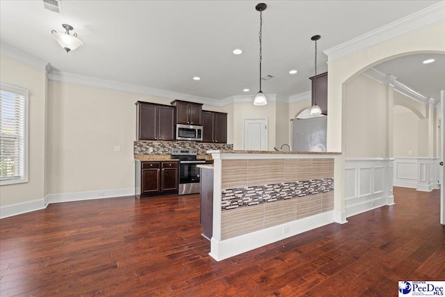1635 Lake Wateree Dr, Florence, SC 29501 - kitchen featuring arched walkways, dark brown cabinetry, decorative backsplash, dark wood-type flooring, and appliances with stainless steel finishes