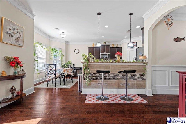 kitchen featuring ornamental molding, decorative light fixtures, dark hardwood / wood-style flooring, and dark brown cabinets