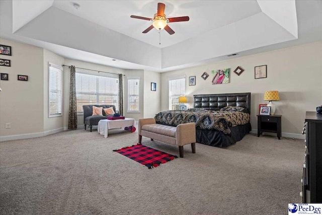 bedroom featuring ceiling fan, a tray ceiling, and carpet floors