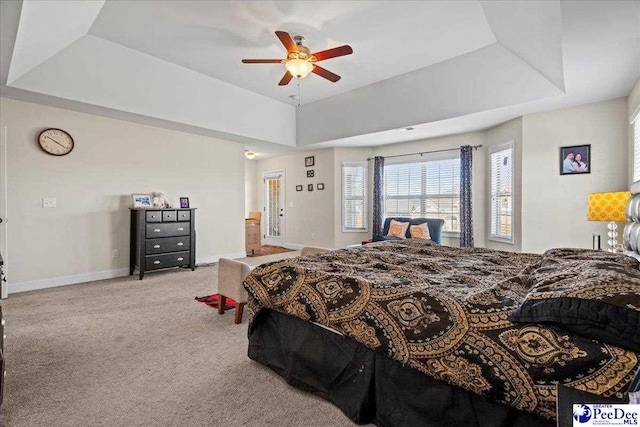 bedroom with ceiling fan, light colored carpet, and a raised ceiling