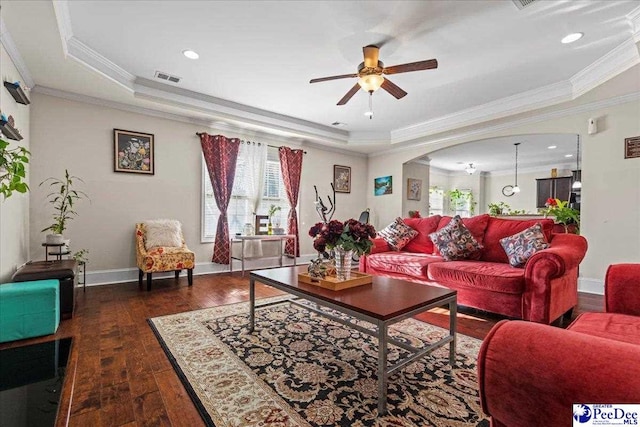 living room featuring ceiling fan, ornamental molding, a tray ceiling, and dark hardwood / wood-style flooring