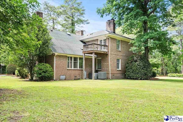 rear view of property featuring central air condition unit, a yard, and brick siding