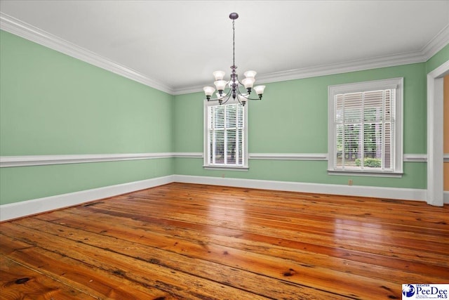 unfurnished room with a chandelier, baseboards, crown molding, and hardwood / wood-style floors