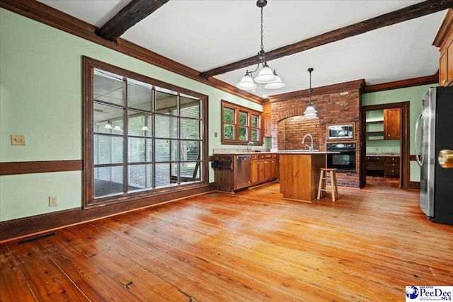 kitchen with stainless steel appliances, beam ceiling, light wood-type flooring, a chandelier, and light countertops