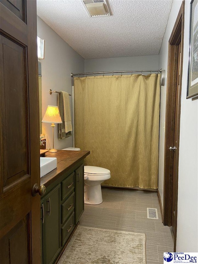 bathroom with vanity, a textured ceiling, and toilet