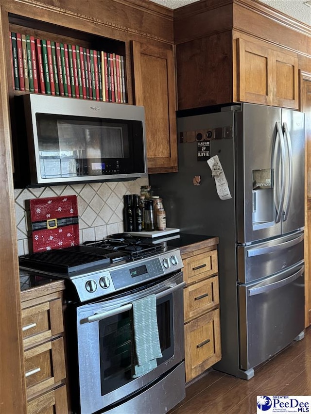 kitchen featuring dark wood-type flooring, stainless steel appliances, tasteful backsplash, and a textured ceiling