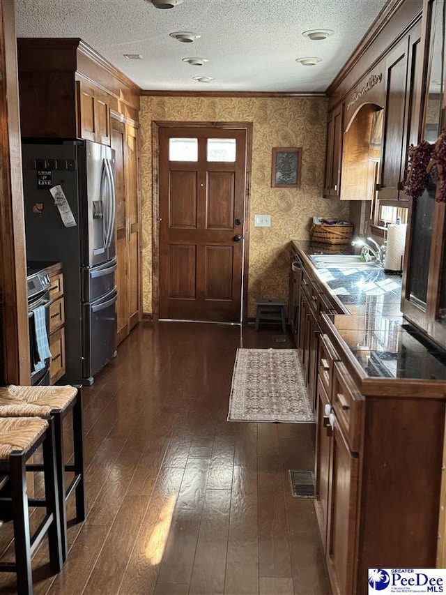 kitchen featuring dark wood-type flooring, crown molding, a textured ceiling, and electric range oven