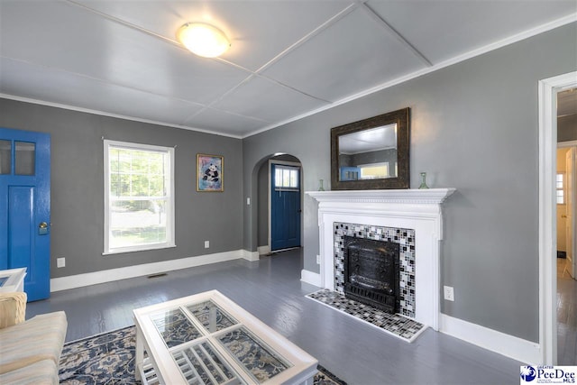 living room with baseboards, arched walkways, wood finished floors, and a tiled fireplace